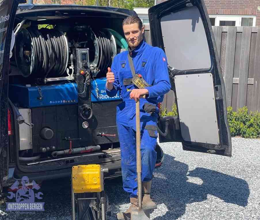 Een monteur bij de werkbus met grote hogedruk-slanghaspels, apparatuur voor hardnekkige afvoerverstoppingen in Bergen