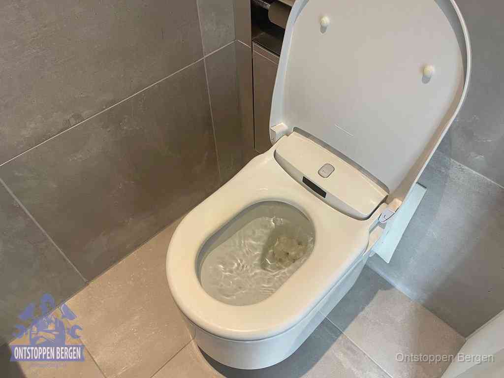 Een toiletpot vol troebel water met drijvend papier en restanten, de meest voorkomende oorzaak van een verstopte wc in Bergen