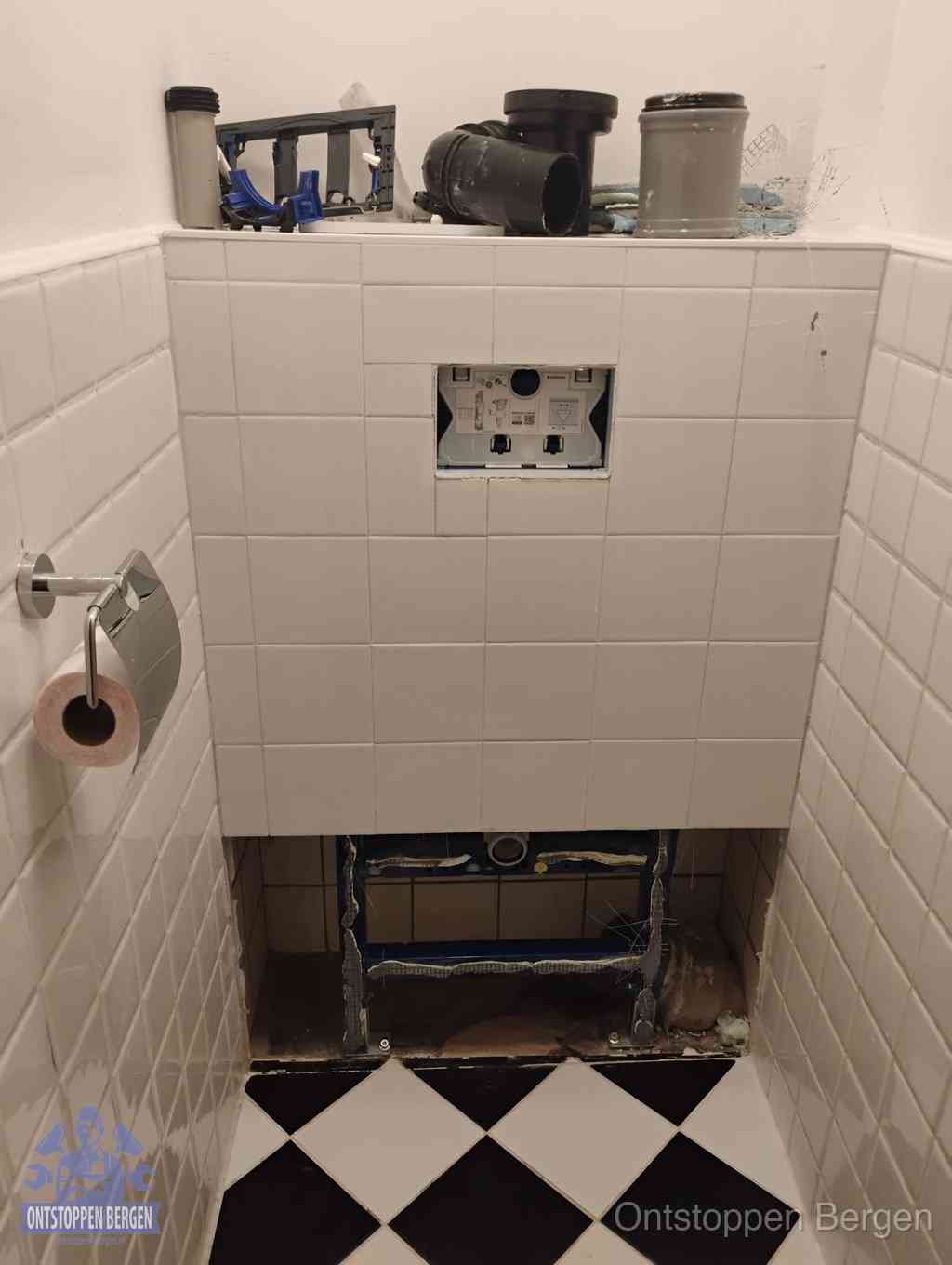 Een toiletruimte waar het hangtoilet en de inbouwreservoir-onderdelen zijn vrijgelegd voor onderhoud, periodiek nazicht voorkomt een wc-verstopping in Bergen