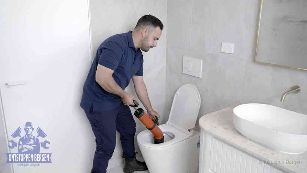 Een monteur gebruikt een handmatige perspomp (toiletontstopper) op een wandcloset tijdens het professioneel wc ontstoppen in Bergen