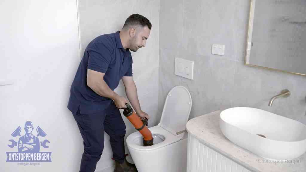 Een man gebruikt een handmatige luchtdruk-ontstopper in een modern betegeld toilet om zelf de wc te ontstoppen in Bergen